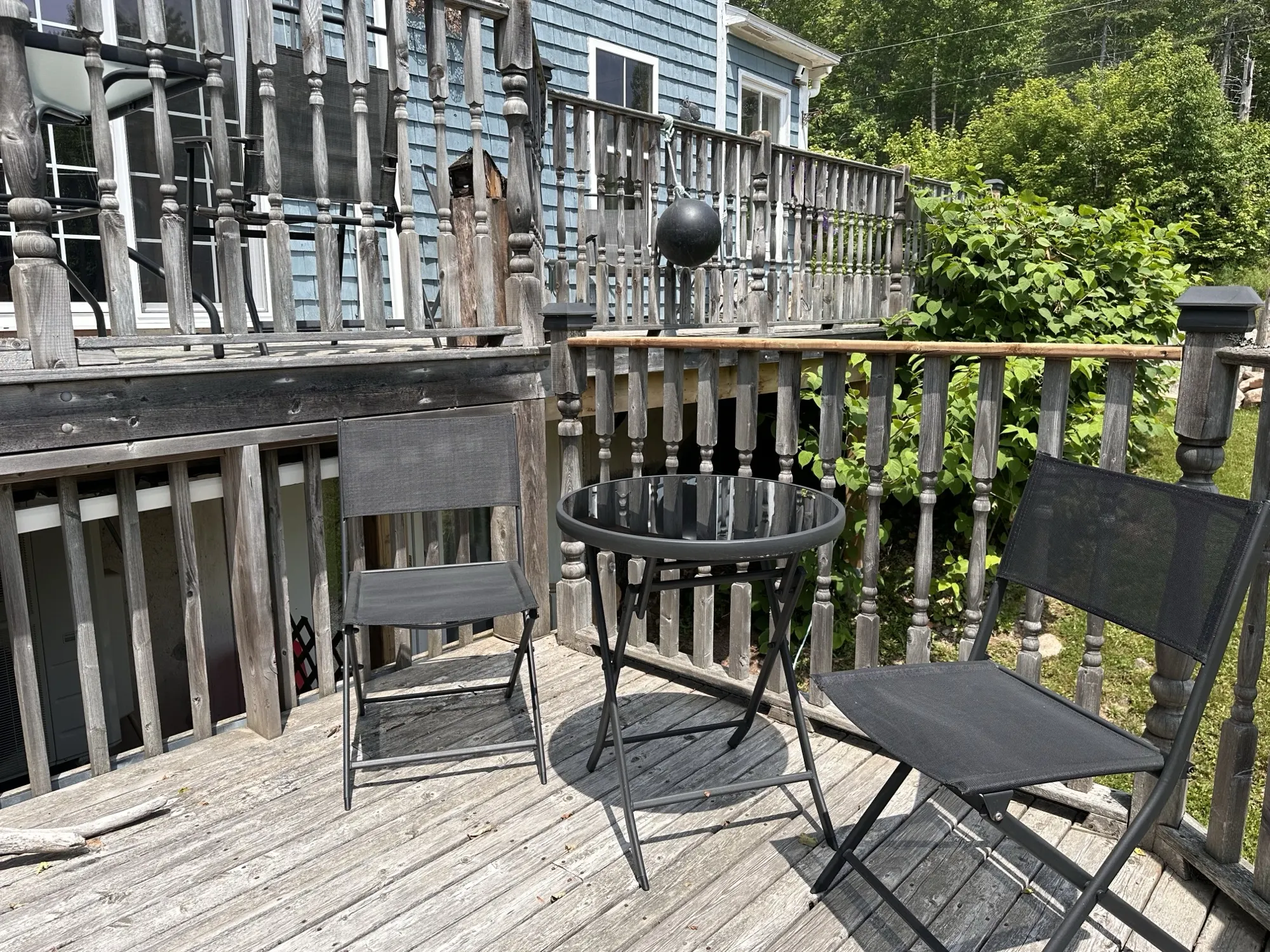 A black bistro table and chairs on the weathered deck