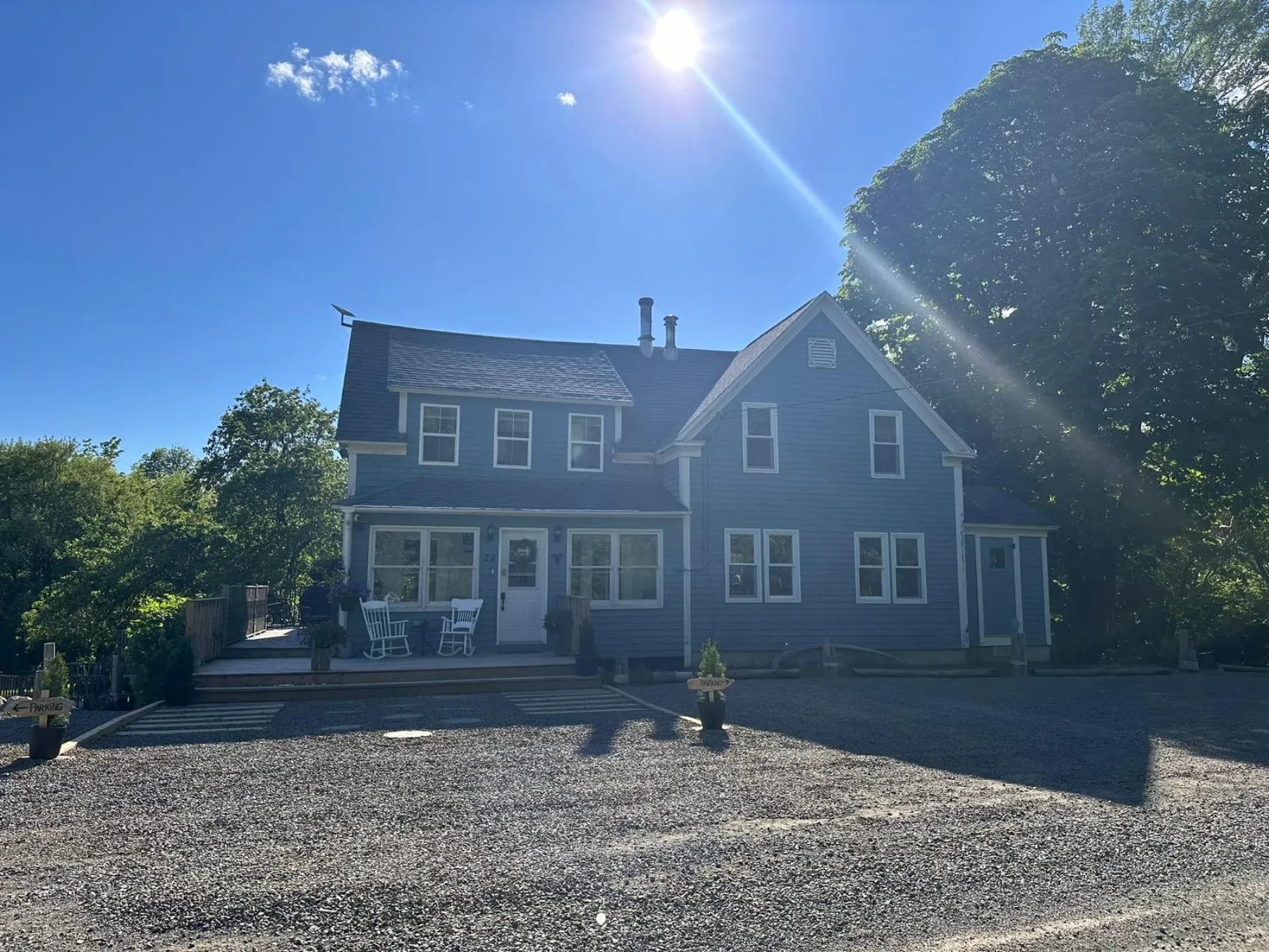 North River Lodge, a blue century home, under a bright sky