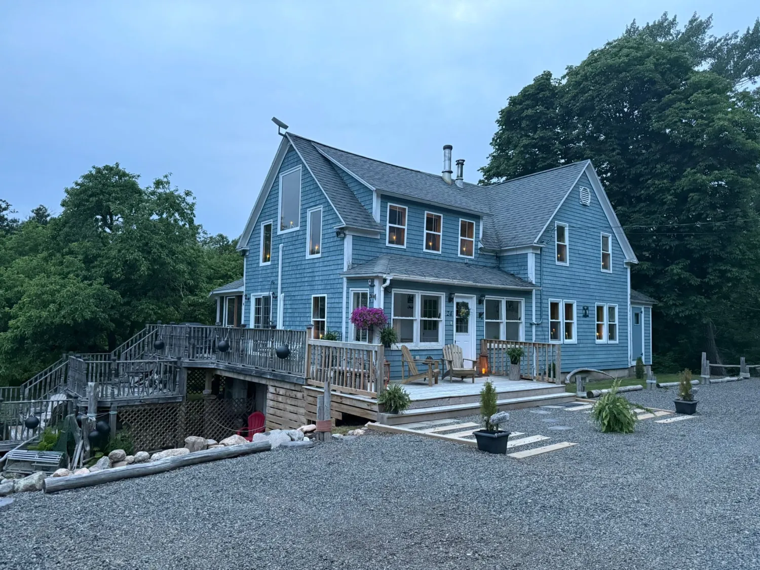The blue heritage home and its sloping lawn at dusk, framed by trees