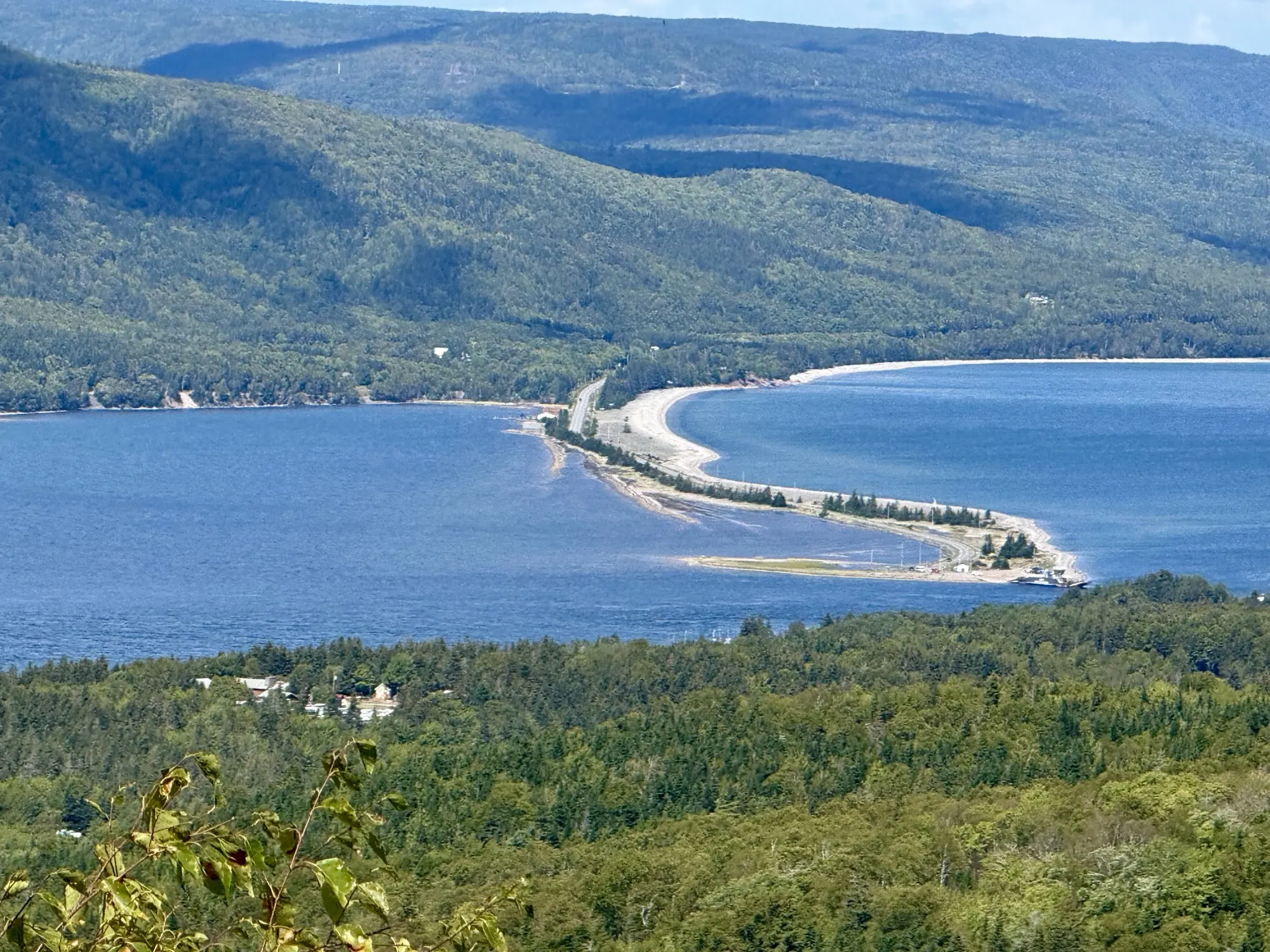 A sandy spit and beach reaching into the water below a coastal village