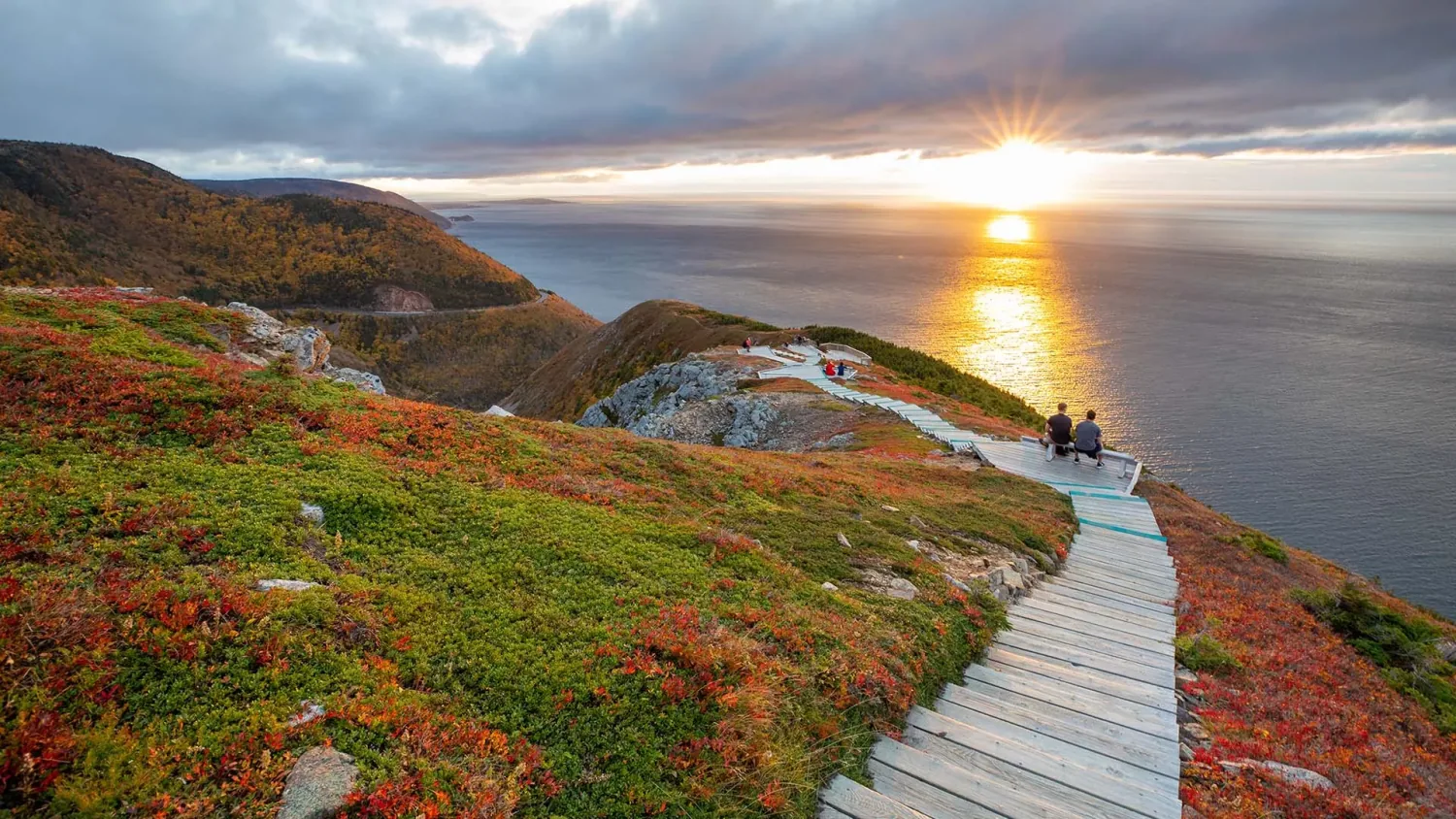 Hikers on the Skyline Trail boardwalk above the ocean at sunset